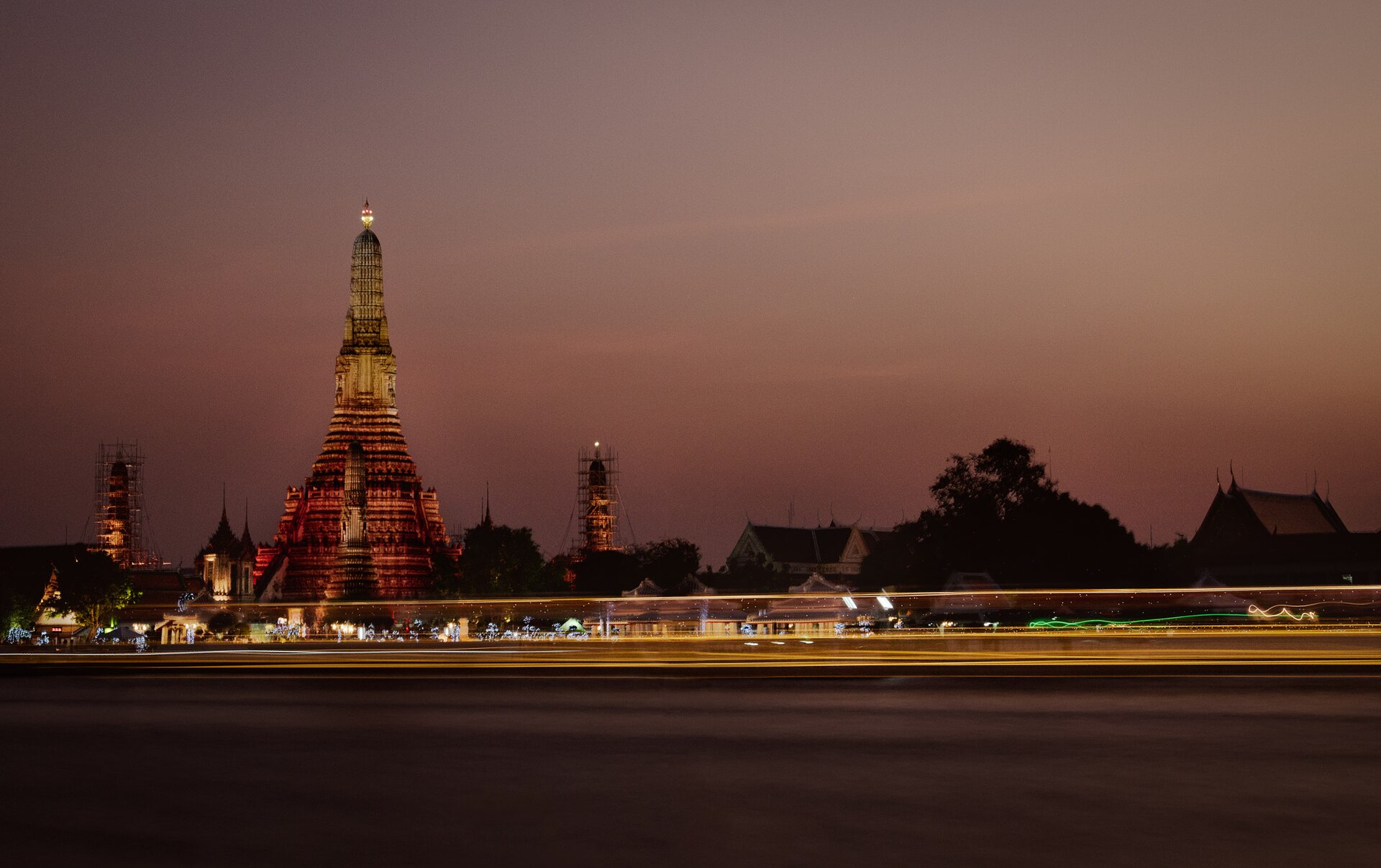 An editorial Bangkok city photograph of Wat Arun beside the river at dusk